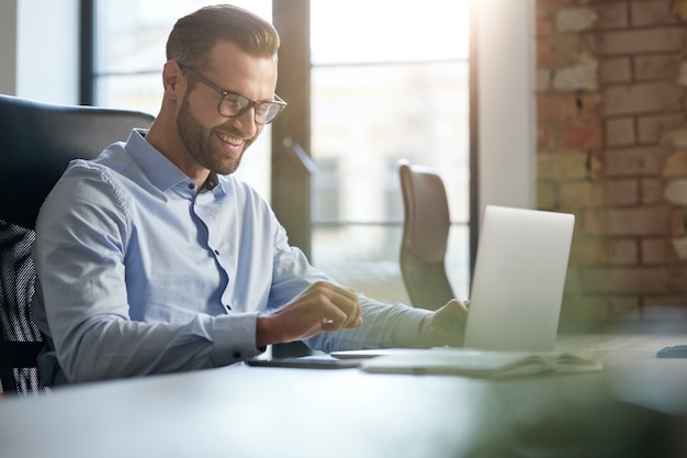 Entusiasta uomo caucasico che lavora in ufficio e sorridente