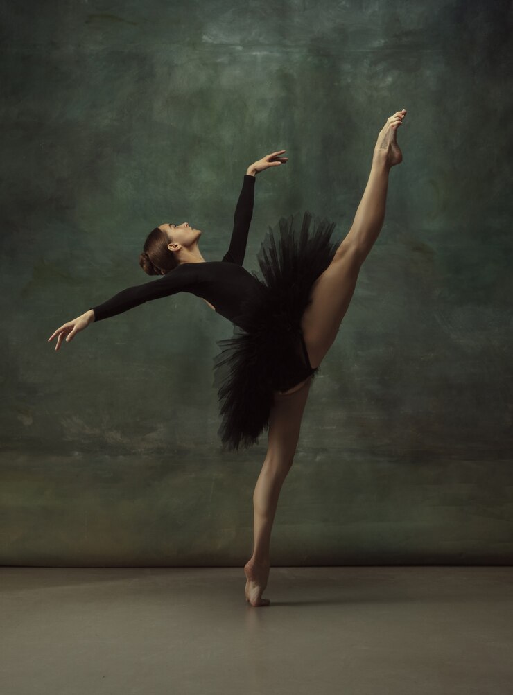 Equilibrato. Graziosa ballerina classica che balla, posa isolata su sfondo scuro studio. Tutù nero di eleganza. Grazia, movimento, azione e concetto di movimento. Sembra senza peso, flessibile. Alla moda.