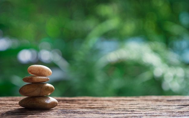 Equilibri le pietre di zen su legno con la priorità bassa verde della natura.