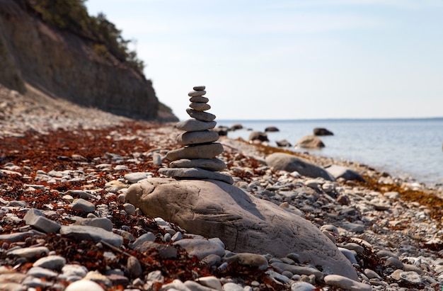 Equilibrio di pietre, pila di ciottoli zen sul mare blu in Estonia. Cielo blu sulla costa soleggiata in estate.