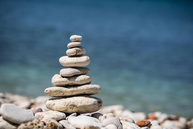 Equilibrio piramide di pietre sul mare. Piccolo pilastro di ciottoli. Un simbolo di calma e tranquillità. Primo piano, sfondo sfocato.