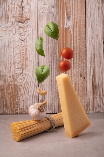 Equilibrio Spaghetti crudi e parmigiano con foglie di basilico e pomodorini su fondo di legno ingredienti per il pesto