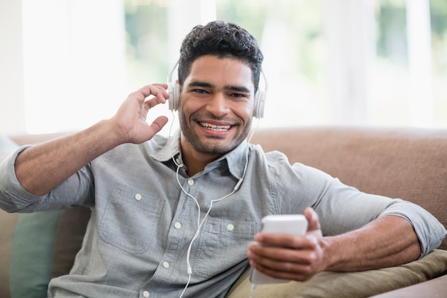 Equipaggi ascoltare la musica sul telefono cellulare in salone a casa