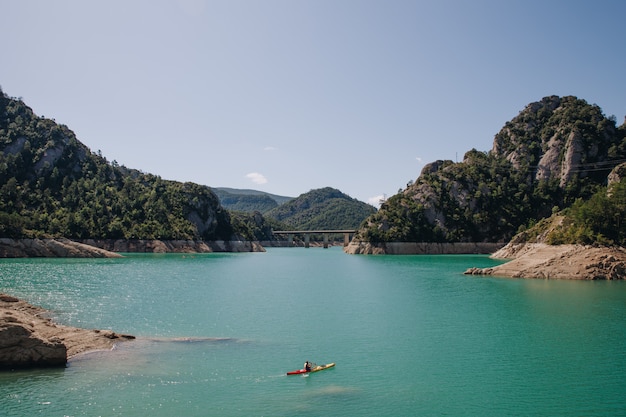 Equipaggi fare il kajak un giorno soleggiato in un lago cristallino circondato dalle montagne sull'estate