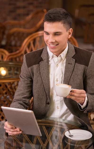 Equipaggi il caffè bevente in caffè e per mezzo del computer della compressa.