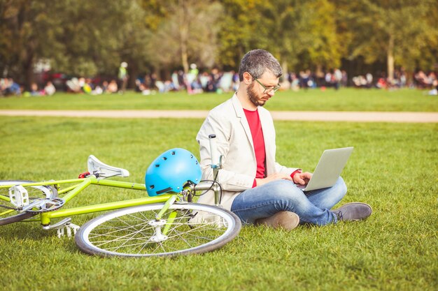 Equipaggi il lavoro con il computer portatile al parco a Londra