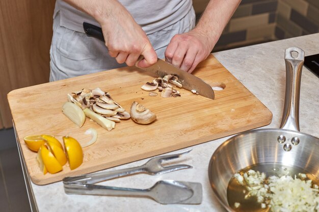 Equipaggi il taglio dei funghi con il coltello sul bordo di legno