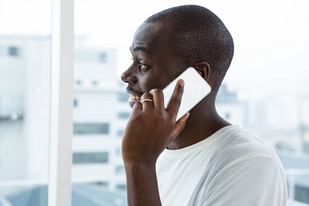 Equipaggi la conversazione sul telefono cellulare vicino alla finestra a casa