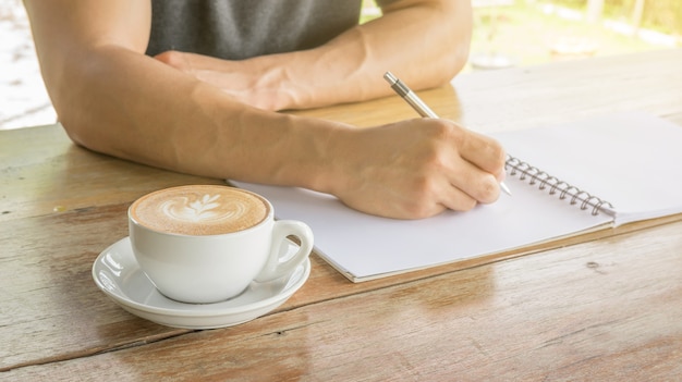 Equipaggi la scrittura su un taccuino in un caffè.