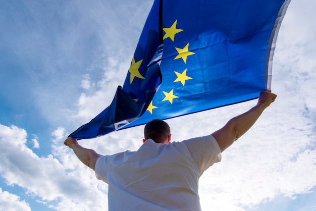 Equipaggi la tenuta della bandiera di UE o della bandiera di Unione Europea, immagine di concetto