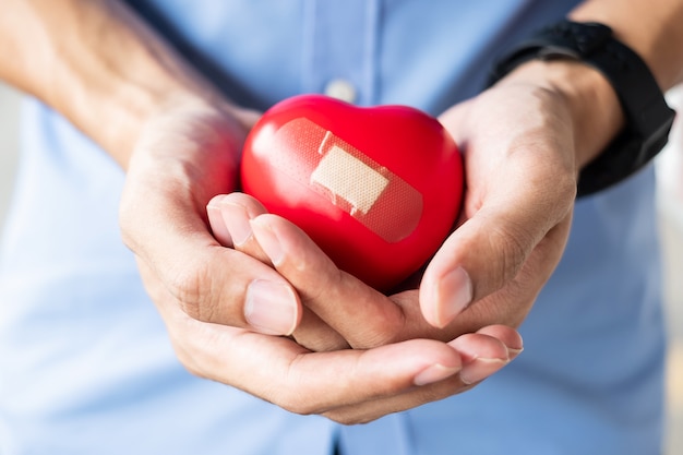 Equipaggi la tenuta della forma rossa del cuore su fondo di legno. Assistenza sanitaria, assicurazione sulla vita