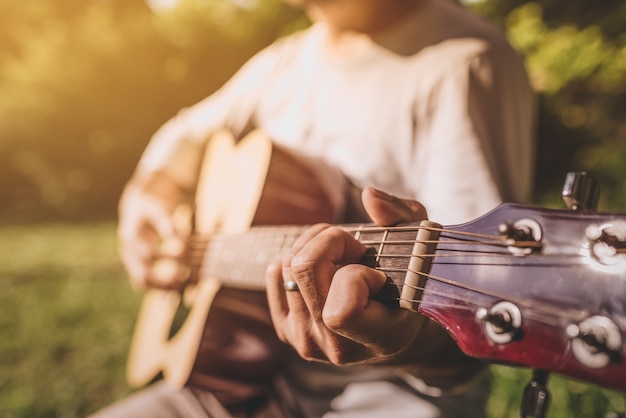 Equipaggi le barrette che giocano la chitarra all&#39;aperto nel parco dell&#39;estate.