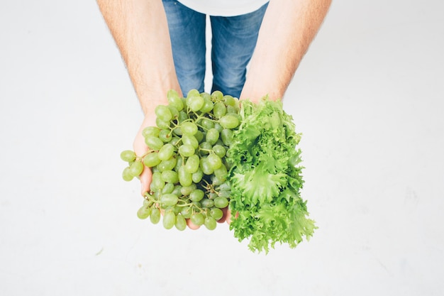 Equipaggi le insalate e l'uva della tenuta, fine su. concetto. isolato su bianco