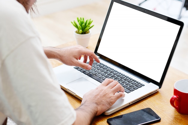 Equipaggi le mani facendo uso del computer portatile con lo schermo in bianco