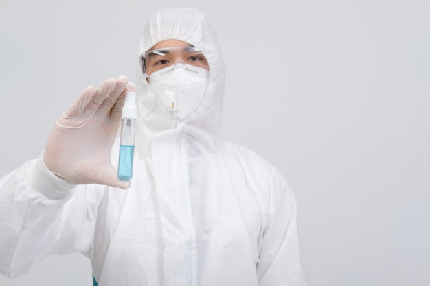 Equipaggi lo scienziato che indossa l'abbigliamento protettivo uniforme biologico, la maschera, i guanti con l'erogatore disinfettante della mano per disinfettare i batteri del virus