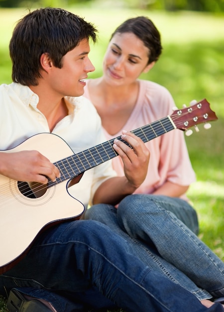 Equipaggi sorridere mentre giocano la chitarra mentre è guardato dal suo amico