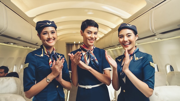 Equipaggio di cabina che applaude le mani in aereo. Trasporto aereo e concetto di turismo.