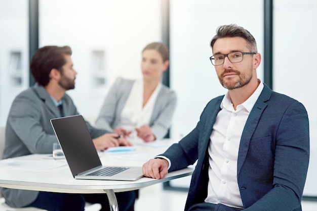 Erano tutti incentrati sull'ispirazione dell'innovazione Ritratto di un uomo d'affari seduto in una sala riunioni con i colleghi in background