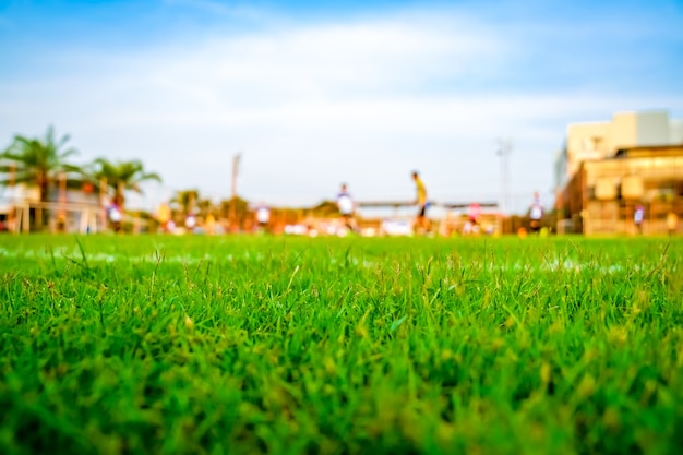 Erba nel campo di calcio con sfocatura giocatore gioca a calcio sfondo.