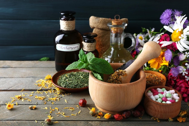 Erbe bacche fiori e pillole sul colore dello sfondo della tavola in legno