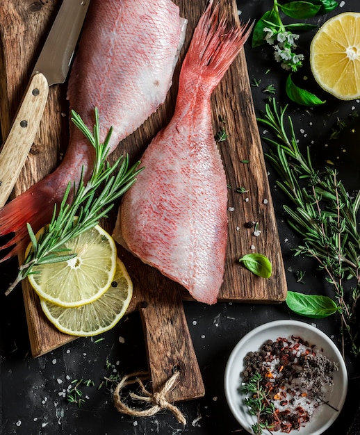 Erbe e spezie fresche di snapper rubino crudo su sfondo scuro Cucinare la cena