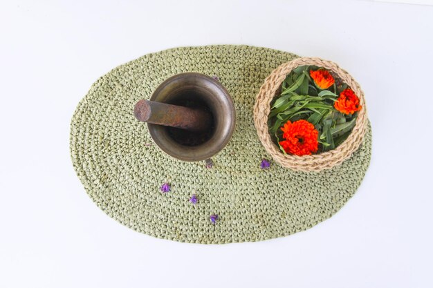 Erbe medicinali Mortaio di rame e piante in un cesto di iuta sullo sfondo del tappeto di vimini Fiori di calendula e achillea