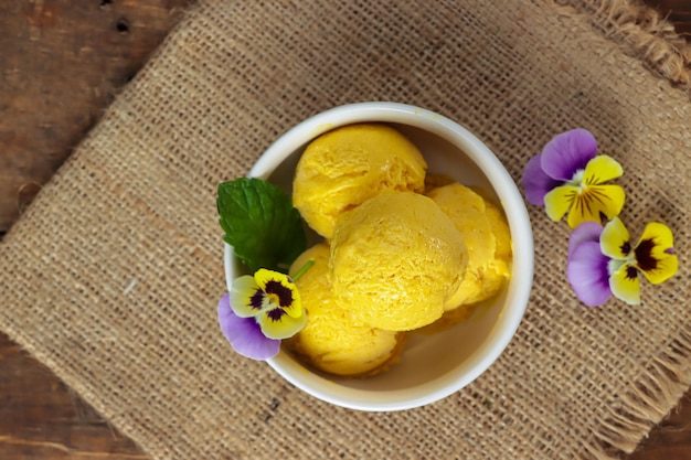 Es krim mangga Sorbetto di gelato al mango con foglie di menta e viola del pensiero di fiori commestibili