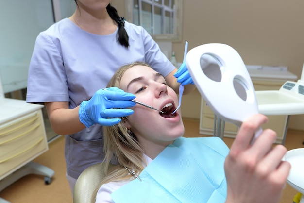 Esame dei denti in una clinica odontoiatrica. Giovane donna seduta su una sedia medica mentre un dentista tratta i suoi denti