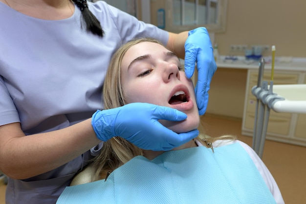 Esame dei denti in una clinica odontoiatrica. Giovane donna seduta su una sedia medica mentre un dentista tratta i suoi denti