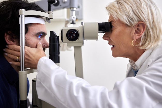 Esame dell'occhio dell'uomo o test con paziente e medico alla consultazione di optometria per lente o montatura per la visione Persona e donna sanitaria con macchina laser per occhi con cura esperta e assicurazione sanitaria