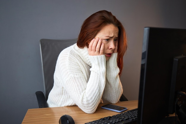 Esaurimento del lavoro. Duro lavoro a distanza. Donna stanca in maglione che lavora o cerca informazioni. Piccola impresa