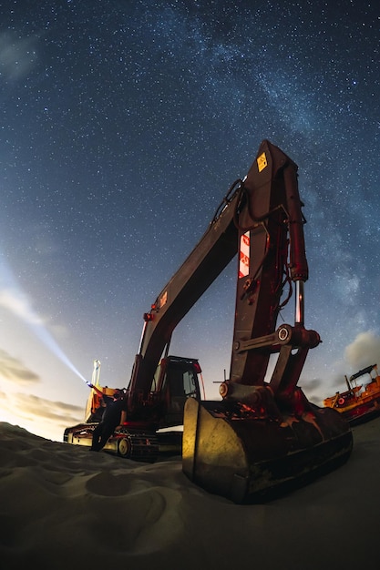 Escavatore che lavora sotto il cielo notturno con la Via Lattea a Valdevaqueros, Cadice, Andalusia