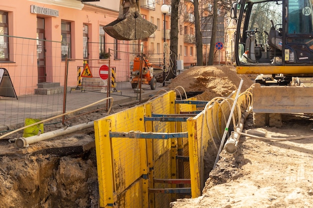 Escavatore che riempie scavi profondi supportati da una cassetta di trincea con ghiaia di piselli durante l'installazione del tubo di drenaggio