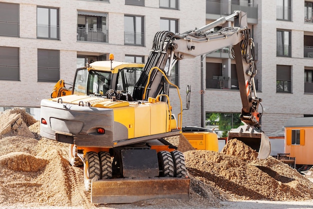 Escavatore che scava in cantiere in controluce Trattore gommato lavori di sterro su strada