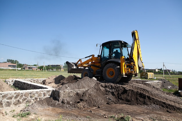 Escavatore e nuova costruzione nel campo. costruire una casa