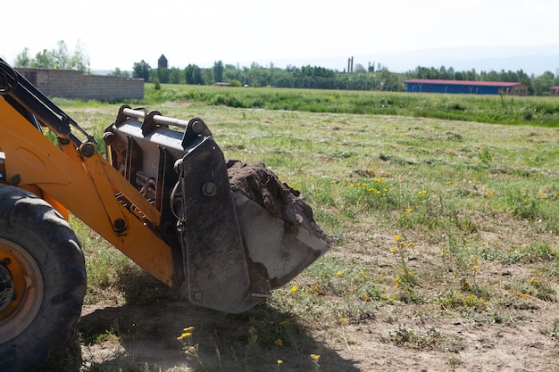 Escavatore e nuova costruzione nel campo. costruire una casa