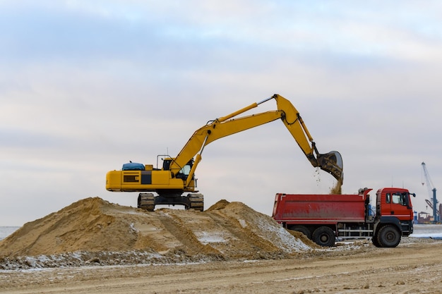 Escavatore giallo che lavora in cantiere La costruzione della strada