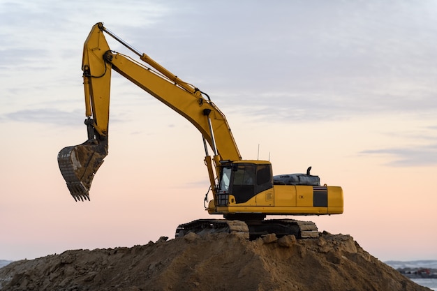 Escavatore giallo lavorando sul sito in costruzione. La costruzione della strada.