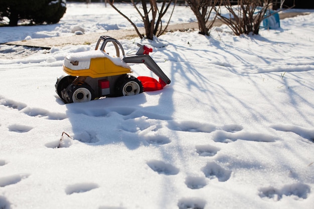 Escavatore giocattolo a colori sulla neve. Concetto sul tempo del letto e rimozione della neve