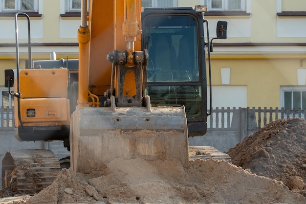 Escavatore in un moderno cantiere Vista di un cantiere attraverso una recinzione in rete metallica