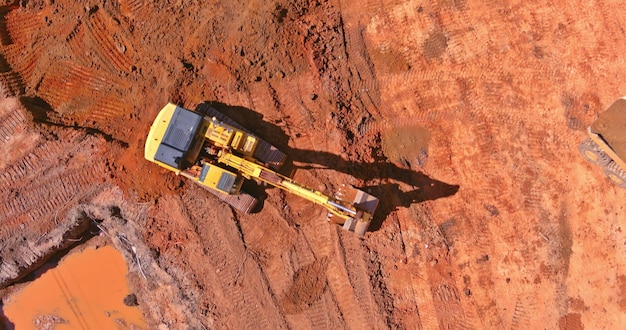 Escavatore su lavori di sterro in escavatore scavare la trincea in cantiere su arial vista dall'alto della terra