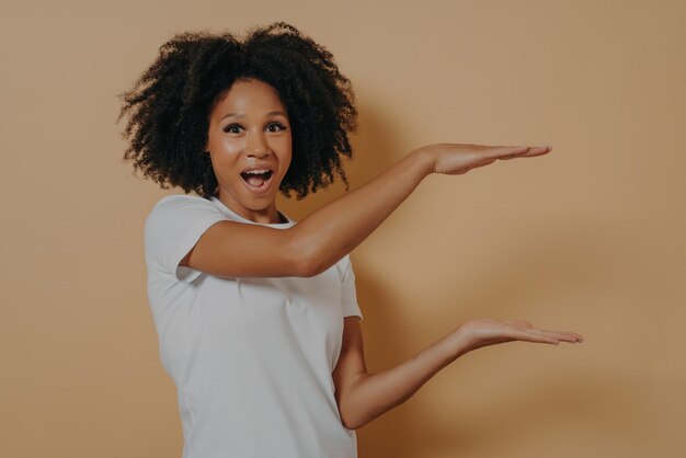 Esce una bella giovane donna afroamericana con i capelli ricci neri che mostra con le mani un esempio di taglia