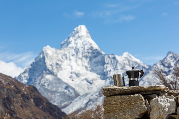 Escursione al campo base dell'Everest. Caffettiera vintage con una tazza a fuoco. lo sfondo di Ama Dablam è sfocato.