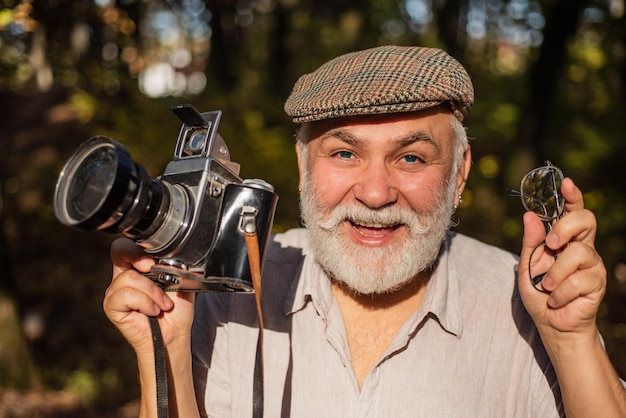 Escursione con la sua attrezzatura fotografica Fotografo vintage e retrò Fotografo senior con fotocamera Stile di vita con la natura Concetto di vacanze stile di vita di viaggio Fotografia naturalistica