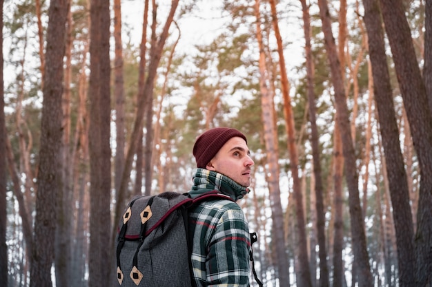 Escursione della persona maschio nella foresta di inverno. Uomo in camicia invernale a scacchi che cammina in splendidi boschi innevati