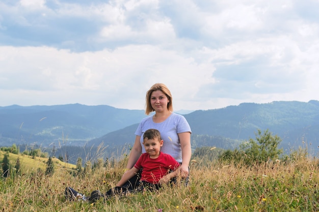 Escursioni in famiglia nella natura. Madre e figlio siedono in alto tra le colline e la foresta.