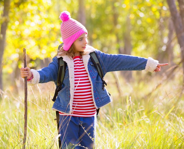 Escursionismo ragazza bambino con lo zaino che punta il dito nella foresta di autum