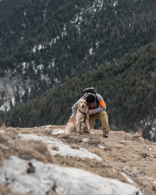 Escursionismo uomo con il suo cane golden retriever in montagna