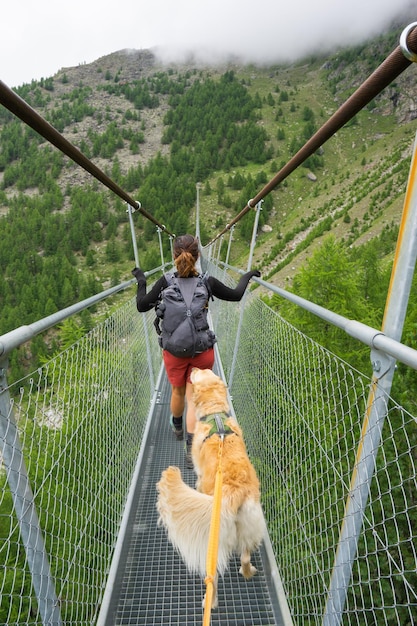 Escursionista attraversando il ponte sospeso con il cane