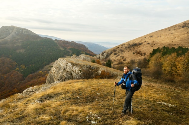 Escursionista barbuto rosso che sale il sentiero del sentiero godendosi il paesaggio Backpacker man climbing mountans